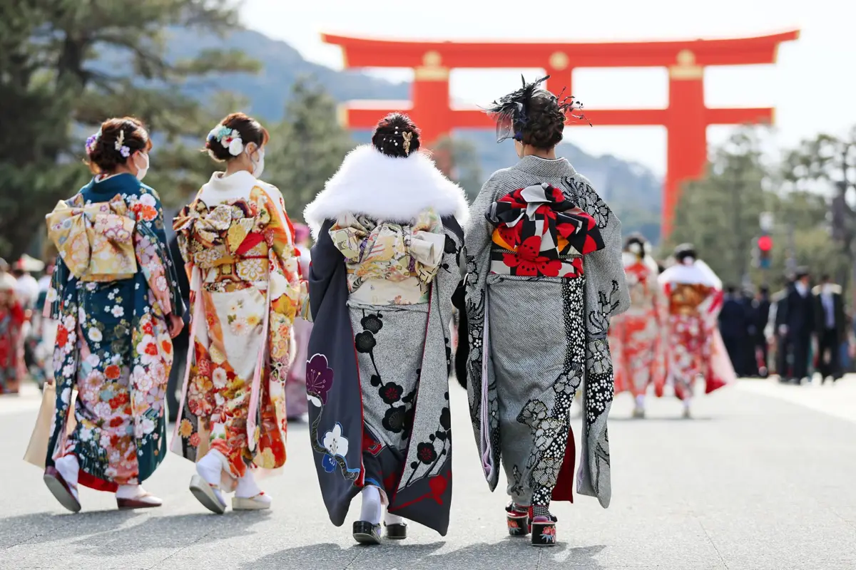 People in kimono walking toward a red torii gate