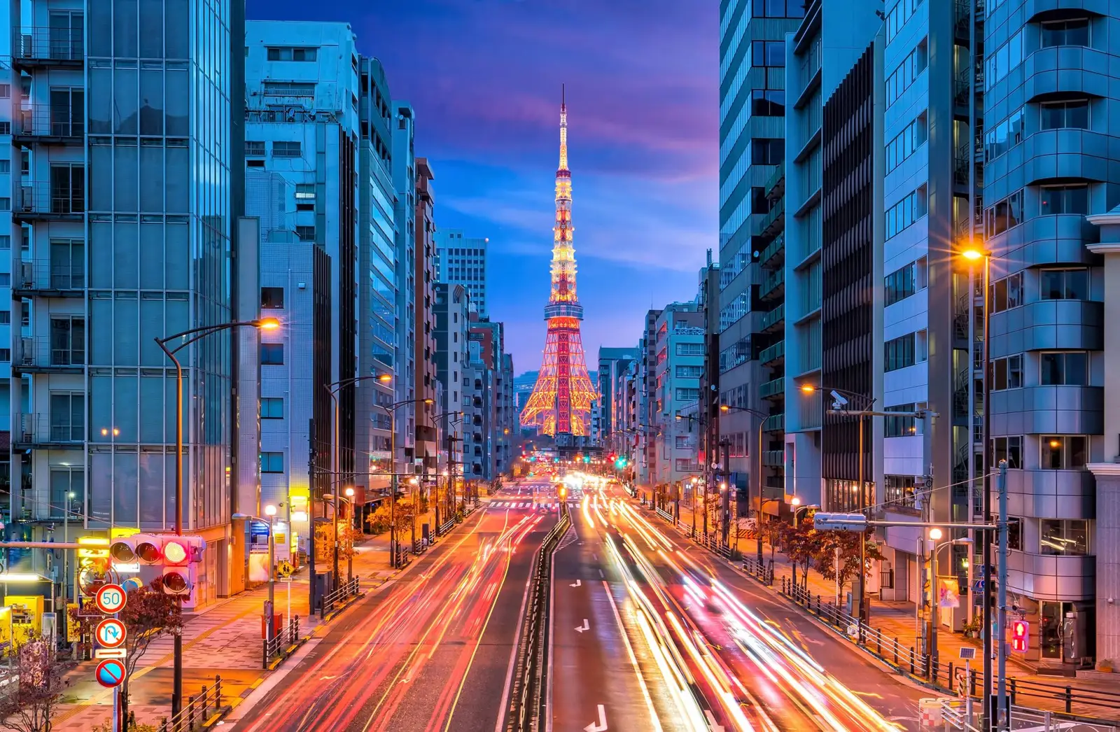 Tokyo Tower at dusk, seen down a street lined with office buildings